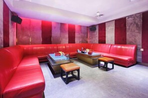 A red leather sofa, a wooden coffee table, and a red cushioned bench in a room with red and white striped walls. - Tianying Hotel (Dongguan)