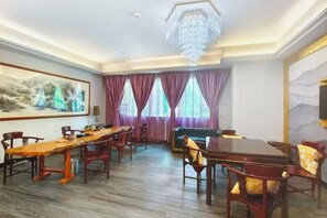 A hotel dining room with a long wooden table, multiple chairs, and a chandelier. - Tianying Hotel (Dongguan)