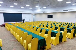 A conference room with rows of tables and chairs, a projector screen, and a whiteboard. - Tianying Hotel (Dongguan)