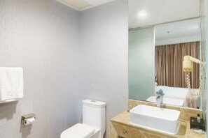 A modern bathroom with a toilet, sink, and mirror. - Tianying Hotel (Dongguan)