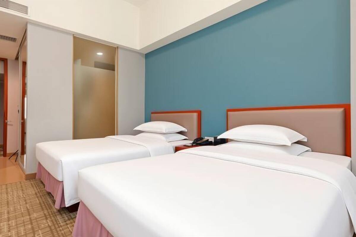 A hotel room with two single beds, a small desk, and a telephone.