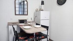 A small kitchen with a dining table, chairs, a refrigerator, a clock, and a window with a view. - Quiet, well-located 1 bed 140, secure covered parking  (Lourdes)