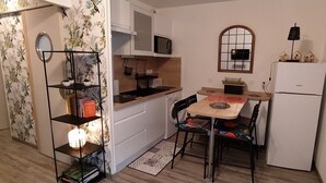 A compact kitchen with white cabinets, a microwave, a sink, and a refrigerator. There is a dining table with chairs and a small rug. - Quiet, well-located 1 bed 140, secure covered parking  (Lourdes)