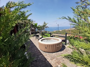 A hot tub surrounded by greenery, a barbecue area, and a scenic view of the sea. - Villa Nova Madeira no Funchal Casa A e B (Funchal)