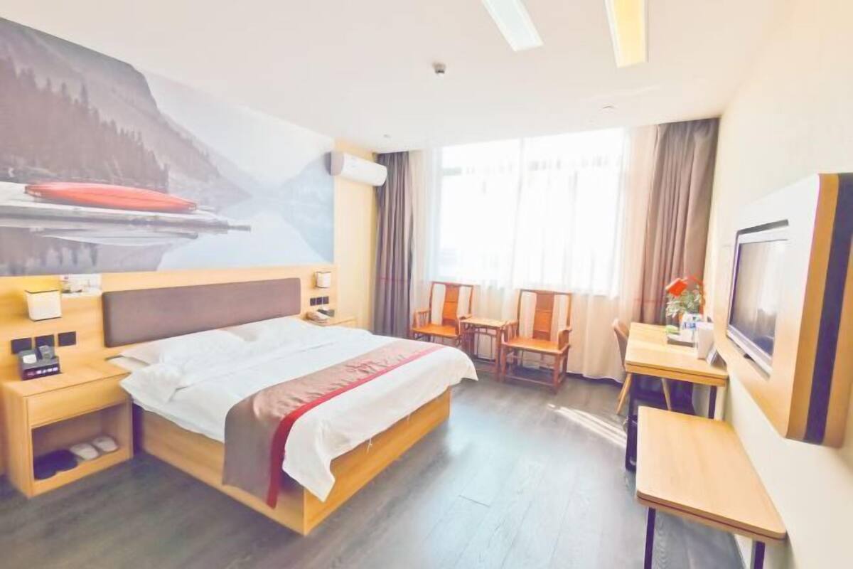 A hotel room with a bed, bedside tables, a desk, and a chair.