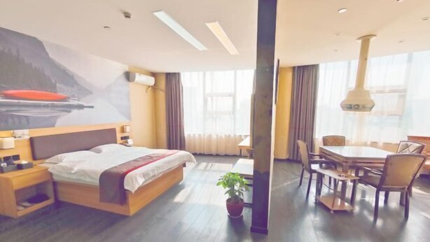 A modern hotel room with a large bed, a dining area with a table and chairs, and a potted plant. - Shankee Hotel (Danyang Railway Station Glasses City) (Danyang)