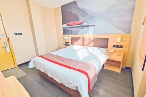 Una habitación de hotel con cama, cabecera de madera, mesitas de noche, teléfono en la pared y un cuadro de un paisaje montañoso.