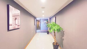 A hallway with a potted plant, framed pictures on the walls, and a tiled floor. - Shankee Hotel (Danyang Railway Station Glasses City) (Danyang)