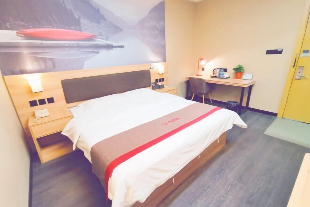 Een hotelkamer met een bed, bureau, stoel en uitzicht op een berglandschap.