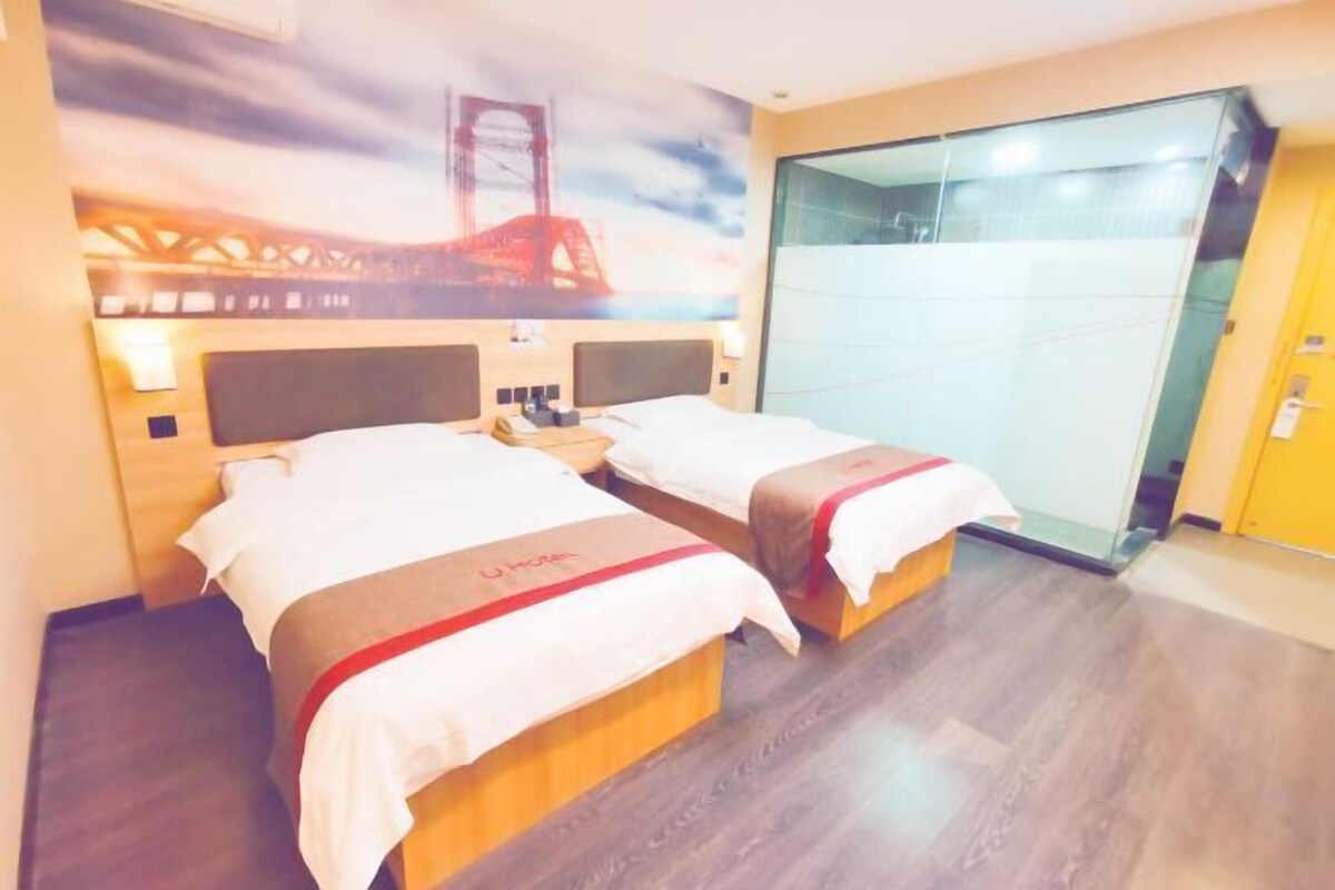 Een hotelkamer met twee bedden, een muurschildering van een brug en een schuifdeur.