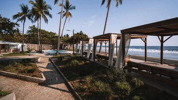 Un resort frente a la playa con piscina, asientos al aire libre y vistas al océano.