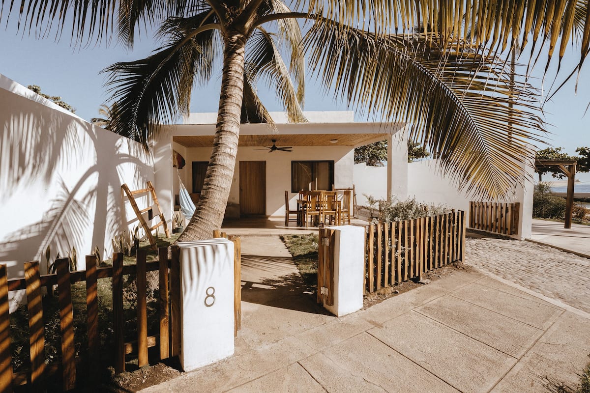 A modern villa with a patio, palm trees, and a view of the sea.