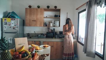 Een keuken met houten kastjes, een koelkast en een raam met gordijnen.