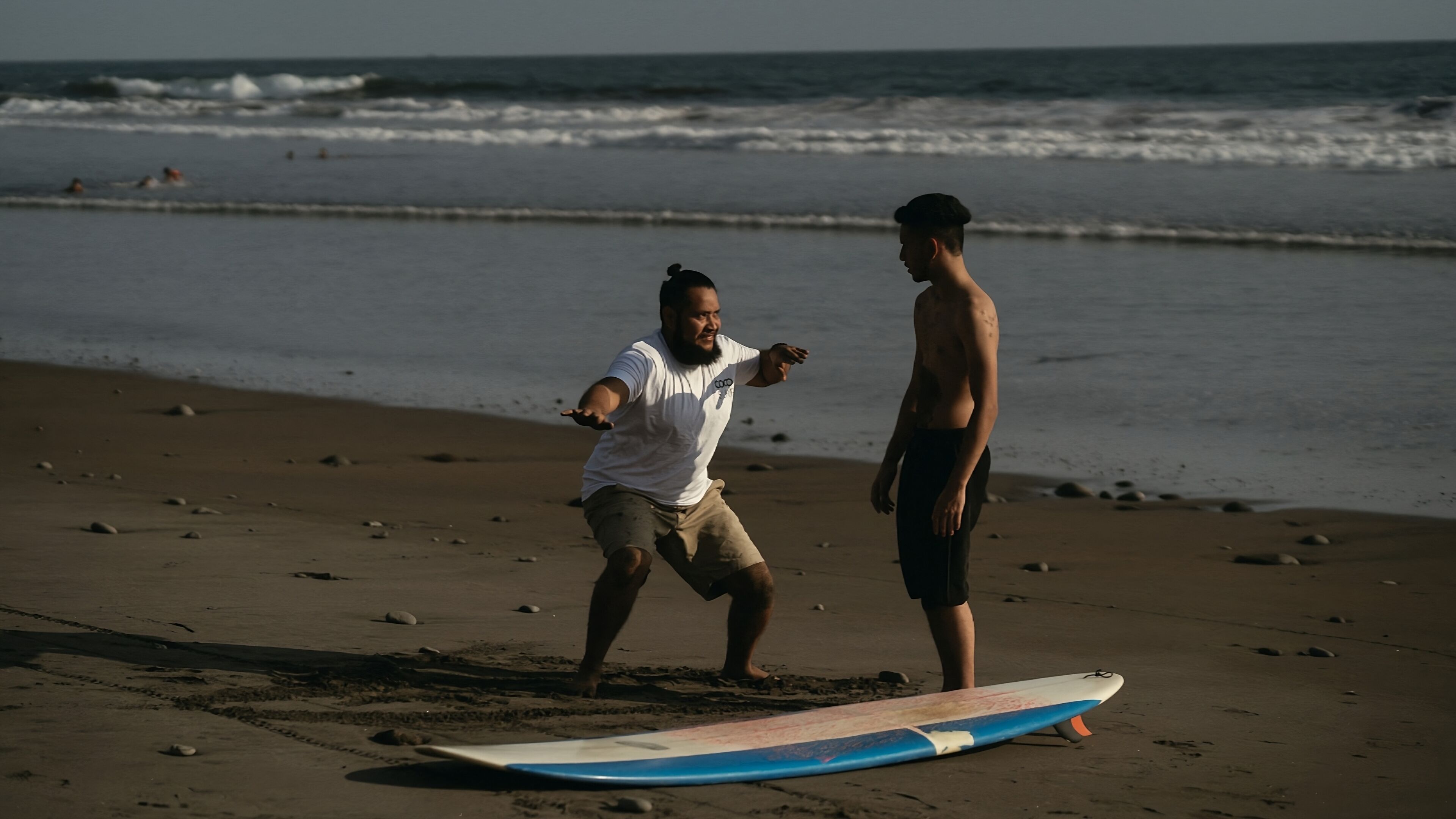 Dos personas en una playa con una tabla de surf.