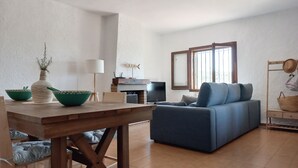 Ein Wohnzimmer mit einem blauen Sofa, einem Holztisch und einem Fernseher.