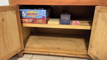 A wooden cabinet with a DVD player on top and board games like Balderdash and JUMBLING TOWER on the shelves.