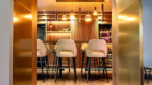 A modern kitchen with a central island, bar stools, pendant lighting, and a wooden finish. - Amicitia (L'Isle-Adam)