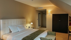 A hotel room with a large bed, a bedside table with a lamp, a chair, and a wardrobe. - Amicitia (L'Isle-Adam)