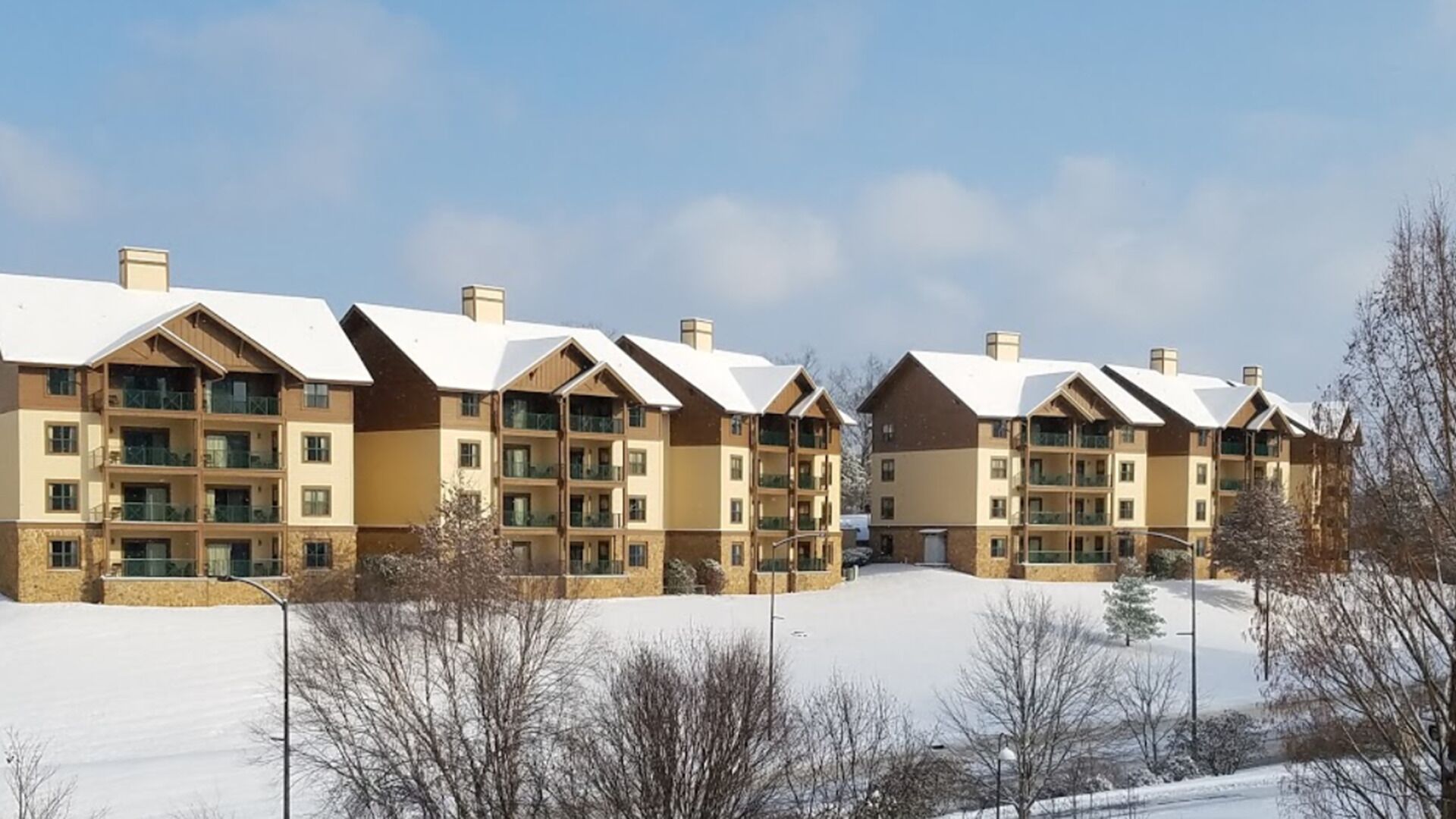 A row of multi-story buildings with balconies, likely a hotel or apartment complex, set in a snowy environment.