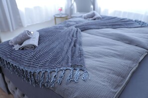 A neatly made bed with a grey blanket and a rolled towel on the side. - Boutique Hotel (Bad Salzuflen)