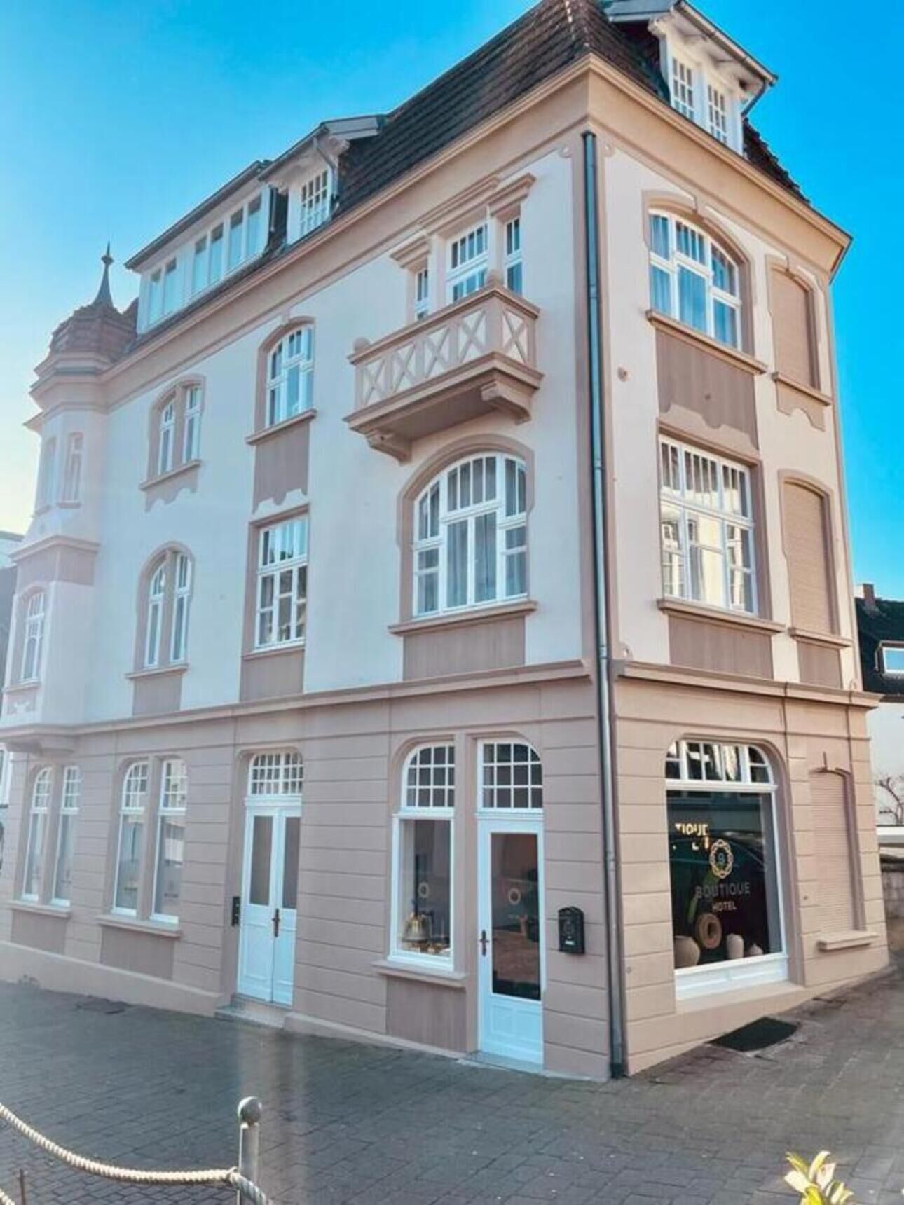 A multi-story building with a boutique hotel on the ground floor, featuring large windows and a classic architectural style.