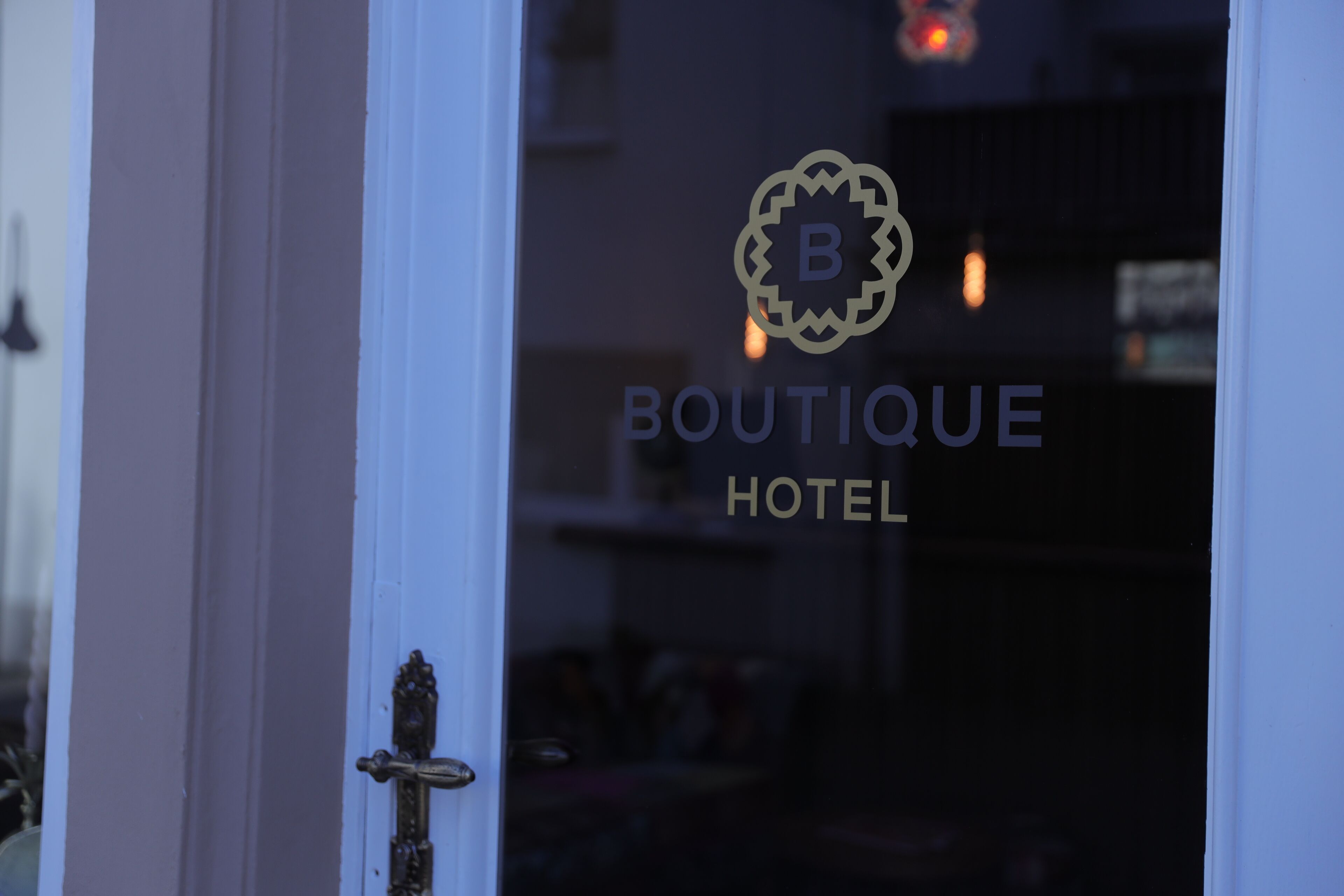 Ein Hotel Eingang mit einer Tür und einem Logo mit dem Buchstaben 'B' und dem Schriftzug 'BOUTIQUE HOTEL'.