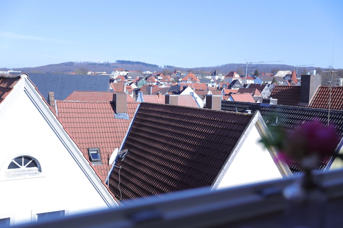 Blick auf eine Stadt mit roten Ziegeldächern und ein Gewässer im Hintergrund.