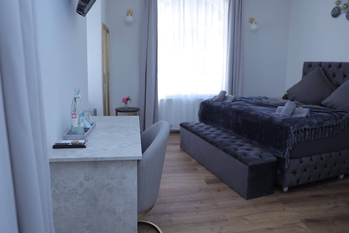 Ein modernes Schlafzimmer mit einer grauen Schlafcouch, einem kleinen Nachttisch und einem Schreibtisch mit Stuhl.