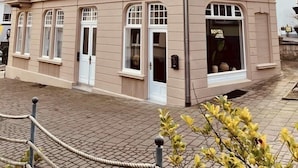 Um edifício de vários andares com estilo arquitetônico tradicional, apresentando um acesso no térreo com uma placa que diz