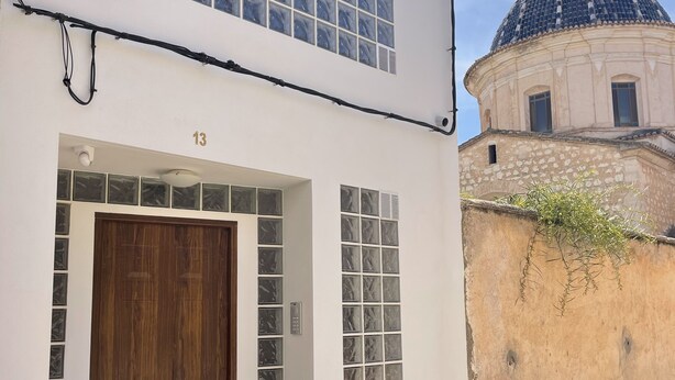 Un edificio con puerta de madera, número 13, y una estructura abovedada al fondo.