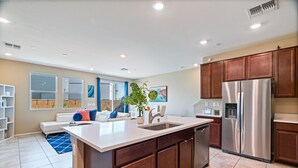 A modern kitchen with a central island, stainless steel appliances, and wooden cabinets.