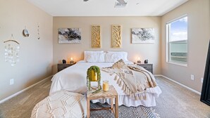 A bedroom with a bed, bedside tables, a ceiling fan, wall art, and a window.