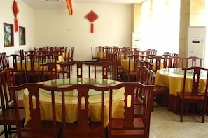 A dining area with round tables, wooden chairs, and yellow tablecloths.