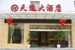 A hotel entrance with a sign, glass doors, potted plants, and red lanterns. - Tianyi Hotel Zhangjiajie (Zhangjiajie)