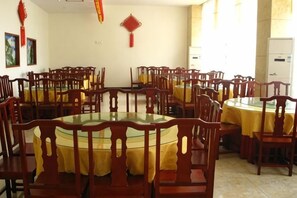A dining area with round tables and chairs, a kitchen area, and a refrigerator. - Tianyi Hotel Zhangjiajie (Zhangjiajie)