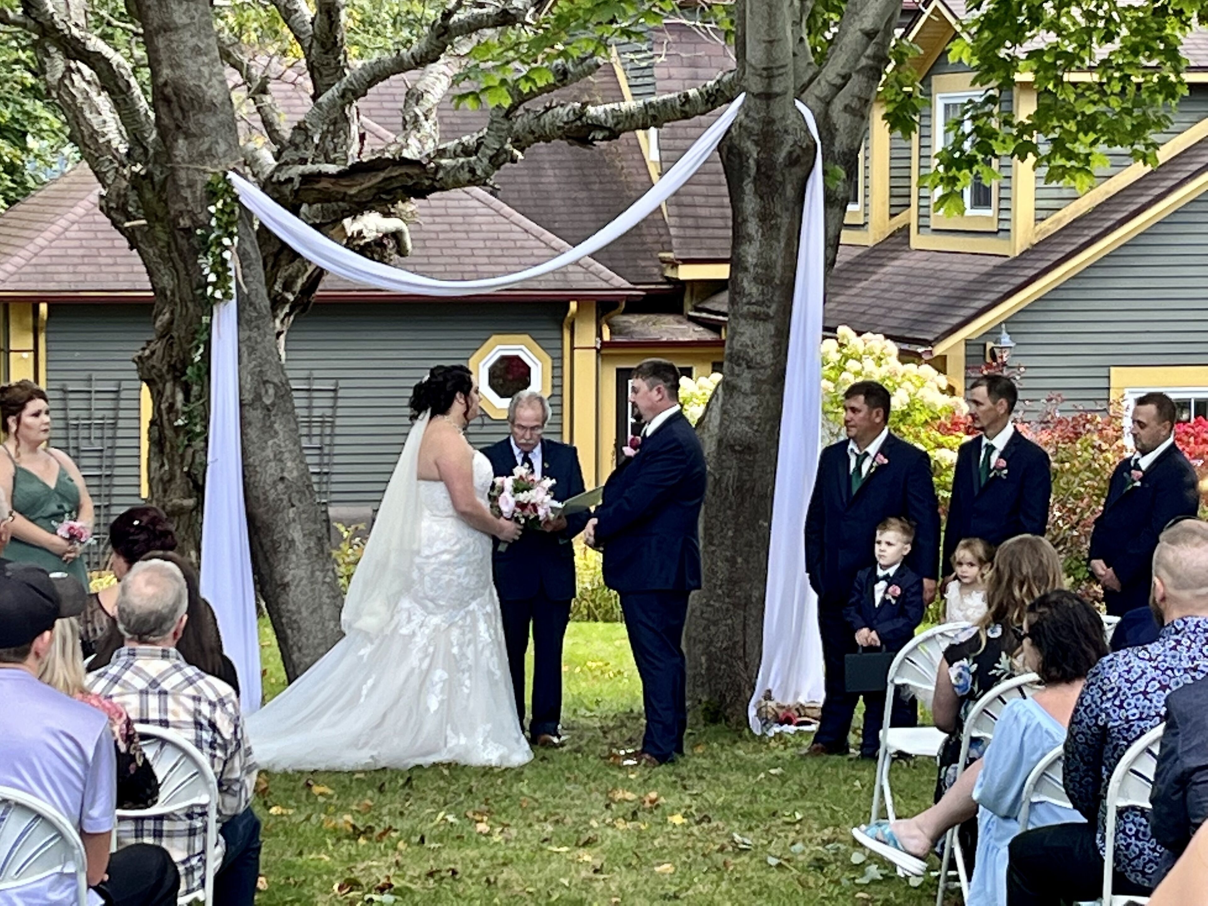 Une cérémonie de mariage en plein air, avec une maison en arrière-plan.