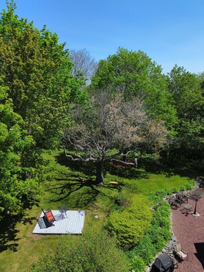 A patio area with a table and chairs, surrounded by lush greenery and trees.