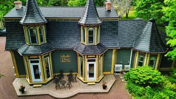 Un edificio grande e histórico con fachada verde oscuro y detalles en amarillo, que presenta un llamativo letrero del Belle View Manor Inn.