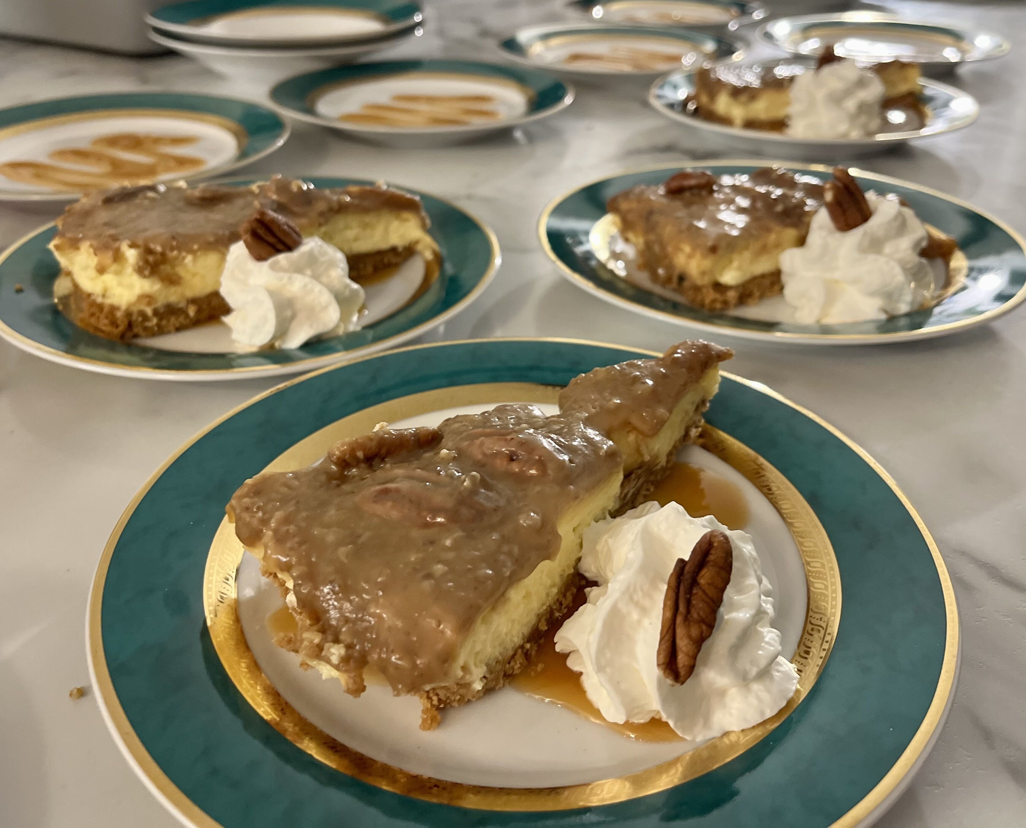 Une assiette de dessert avec une part de tarte nappée de sauce au caramel et de noix de pécan, accompagnée de crème fouettée.