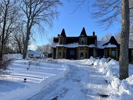 Un edificio grande y oscuro con una entrada destacada y un camino de entrada cubierto de nieve.
