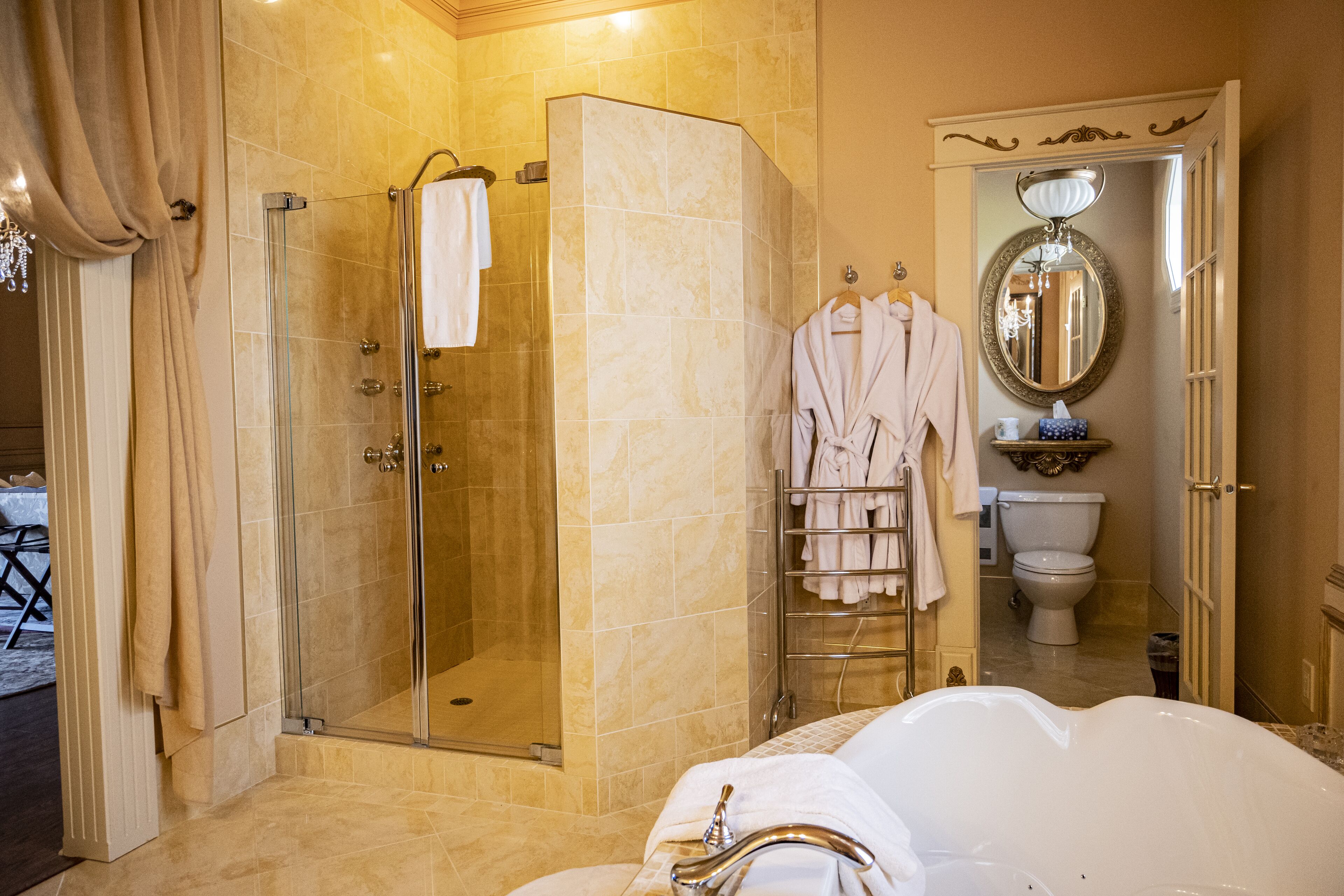 A bathroom with a glass-enclosed shower, a white bathtub, and a toilet.