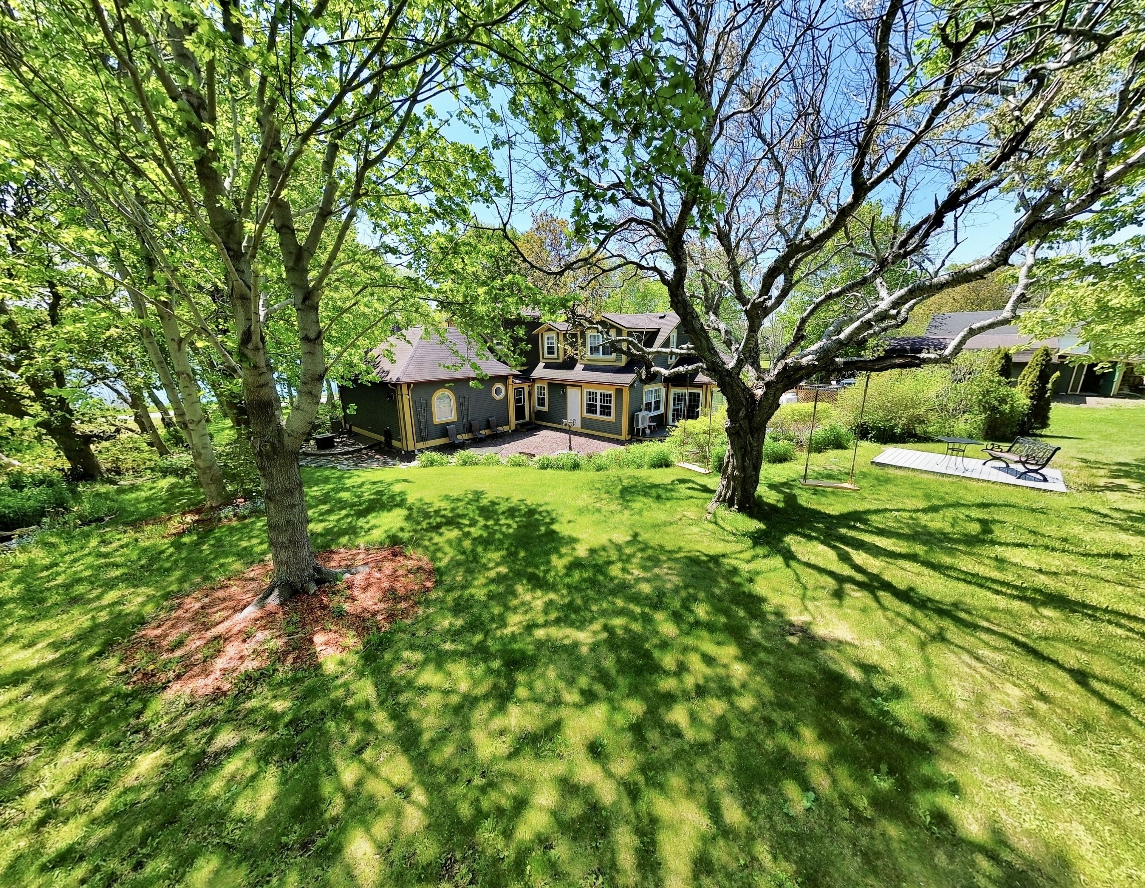A two-story house with a well-maintained lawn, a swing set, and a patio area.