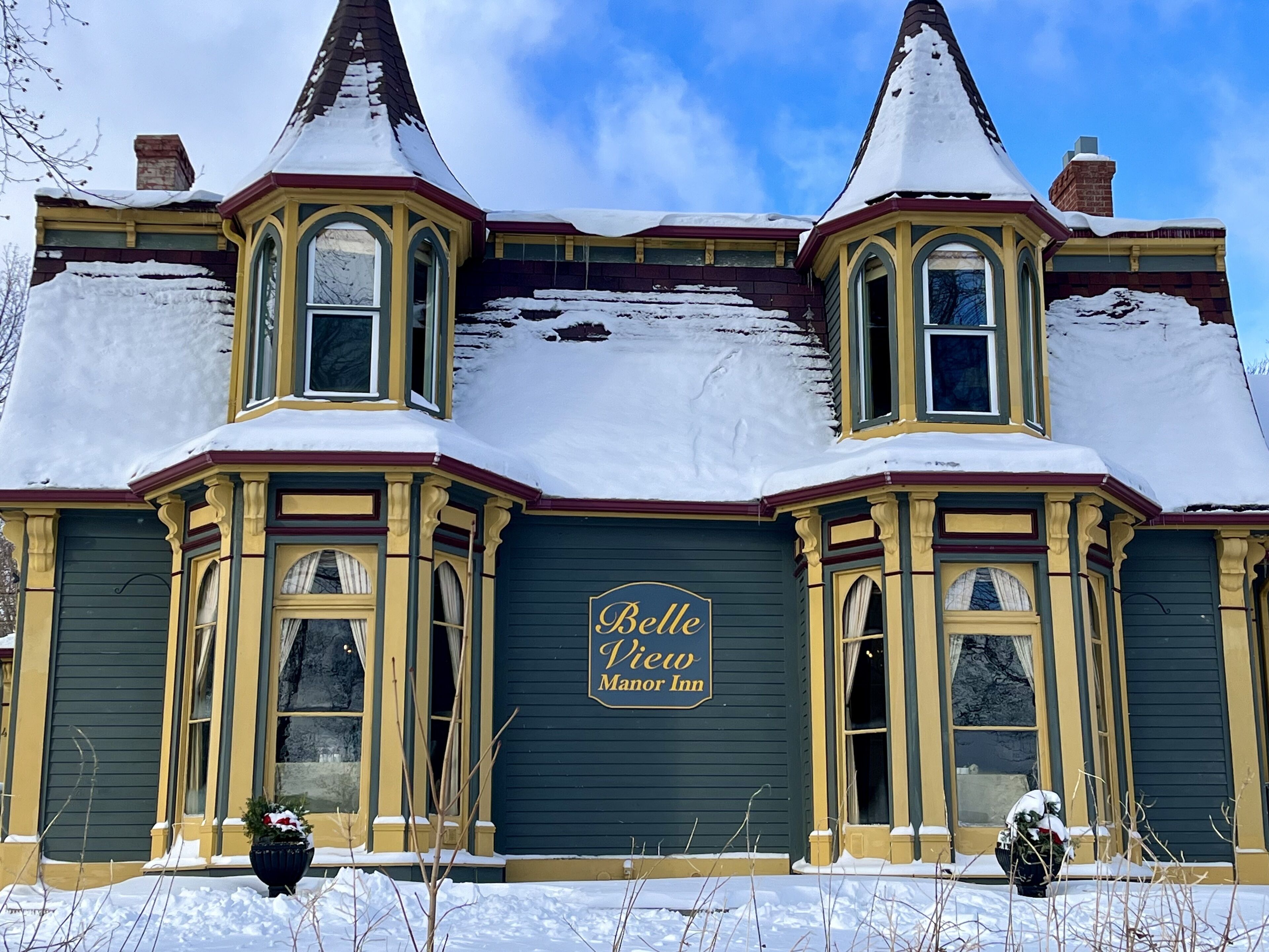 Belle View Manor Inn, a Victorian-style building with snow-covered roofs and a dark green facade.