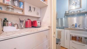 A kitchen with a microwave, toaster, and various kitchen utensils on the counter. - Serene Studio Hideaway, Kensington and Chelsea (London)