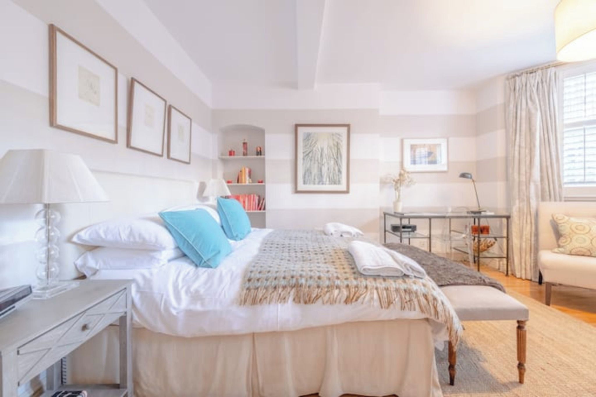 A well-lit bedroom with a bed, bedside tables, a desk, and a chair.