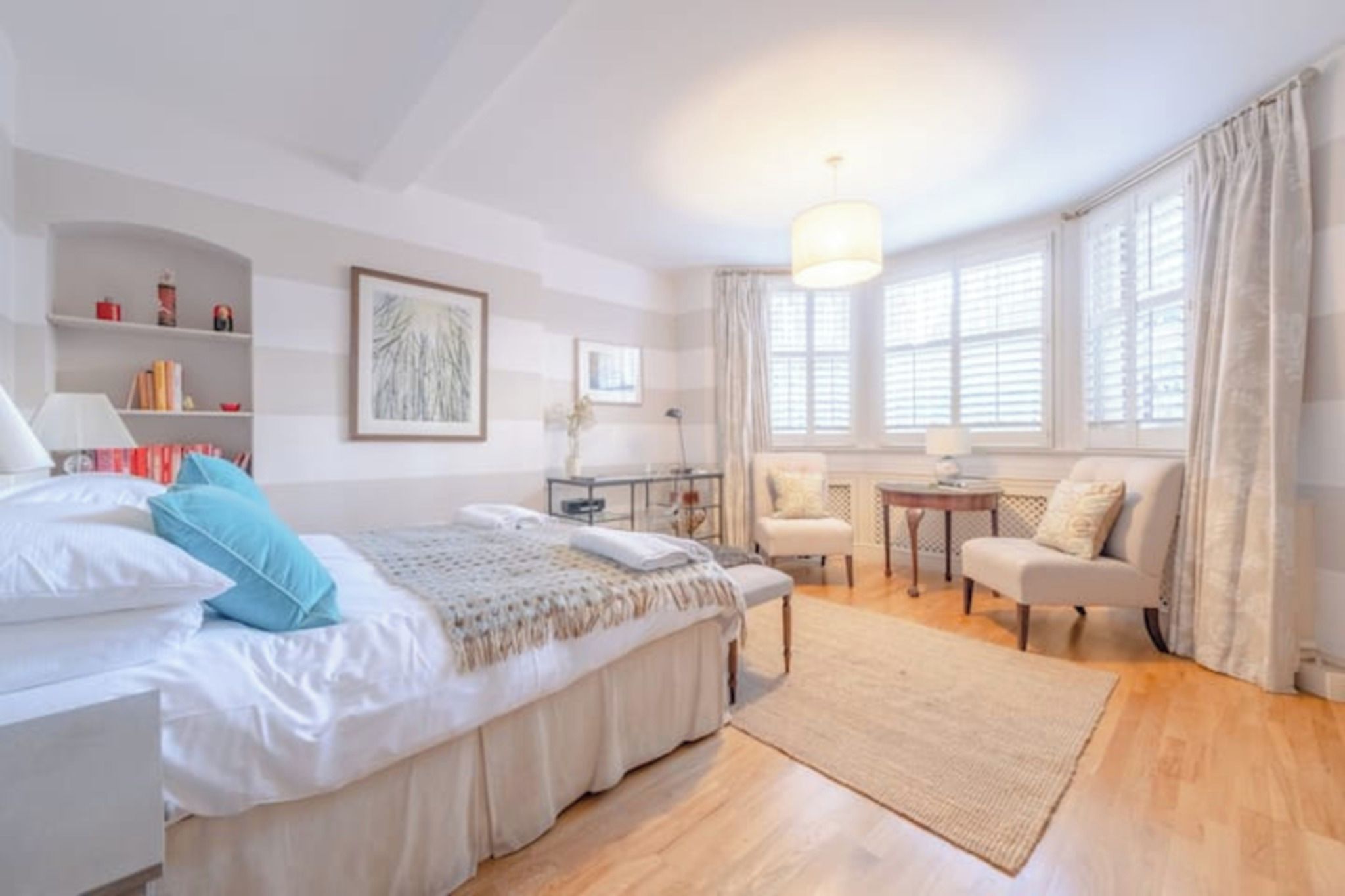 A bedroom with a bed, bedside tables, a desk, a chair, and a window with curtains.