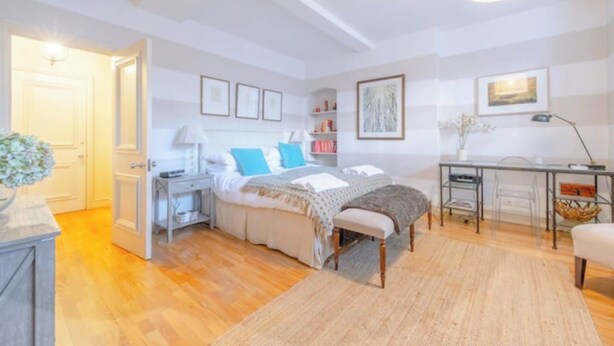 A bedroom with a bed, bedside tables, a desk, and a chair. - Serene Studio Hideaway, Kensington and Chelsea (London)