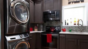 A compact kitchen with a washing machine, a microwave, and an oven.