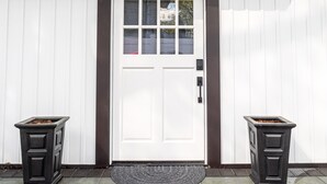 A building with a white door, black trim, and a stone-paved entrance. - Ultra-Modern Studio | Near Hospital & NYCIM | WiFi (Huntington)