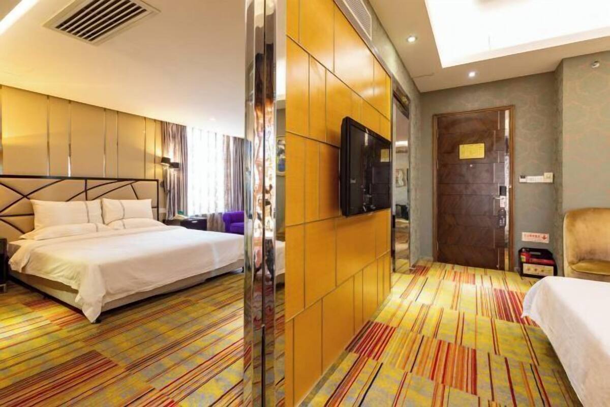 A hotel room with a bed, a TV, a wardrobe, and a door.